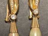 deux paires de boucles d'oreilles en perles et diamants posées sur un fond noir