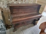 un piano en bois dans une pièce, avec un mur en briques derrière lui