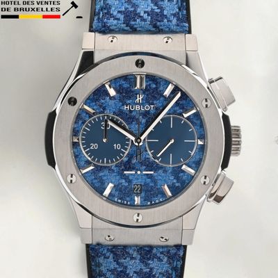 gros plan d'une montre sur une surface blanche avec un bracelet bleu