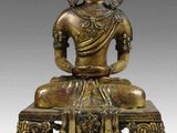 une statue en bronze représentant un Bouddha assis sur un banc