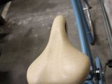 a blue bicycle with a tan seat in a garage
