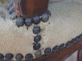 a close up of a wooden chair with black beads on it