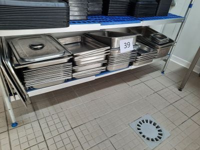 many trays of food sitting on a shelf in the kitchen