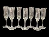 six verres à vin transparents alignés sur un fond noir