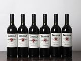 six bouteilles de vin sont alignées sur une table en bois