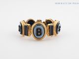 a black and gold bracelet with a letter b on it