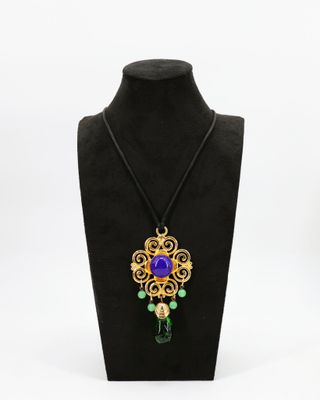 un collier orné d'une fleur violette et de perles vertes, porté par un mannequin noir