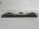 three miniature cars are in a clear display case on a white surface