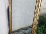 un miroir à cadre doré appuyé contre un mur, devant un mur blanc