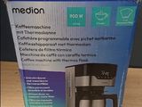 boîte contenant une cafetière posée sur une table, avec une tasse de café à côté