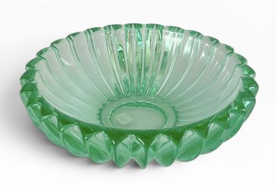un bol en verre vert posé sur une surface blanche