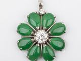a close up of a green flower shaped pendant with a diamond center