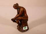 une statue en bronze d'un homme assis sur un rocher