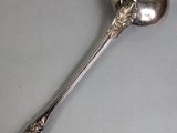 silver spoon with a flower on it sitting on a gray surface