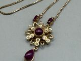 a close up of a necklace with a purple stone on it