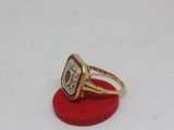 an image of a gold ring with a red stone surrounded by diamonds