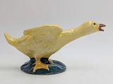 yellow duck figurine sitting on a blue base on a white background