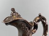 a silver tea pot with a lid on a table