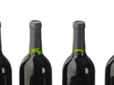 six bottles of wine are lined up in a row on a white surface