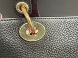 the handle of a black purse with a gold clasp
