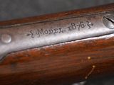 a close up of a rifle with a wooden handle on a black background