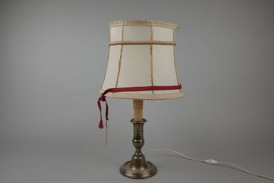 une lampe posée sur une table, ornée d'un ruban rouge