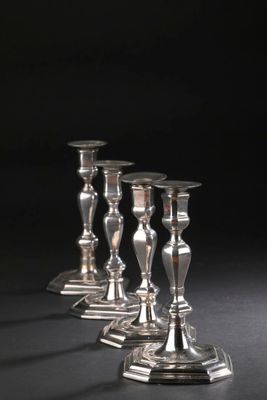 quatre bougeoirs en argent sont alignés sur une surface noire