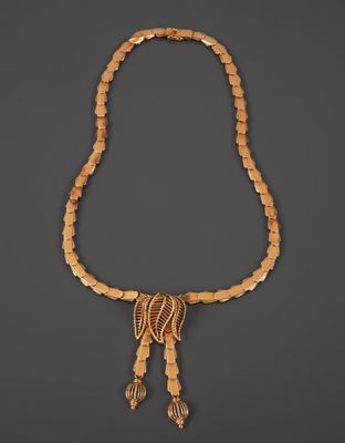 a gold necklace with fringes and beads on a gray background