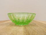 a green glass bowl sitting on a wooden table