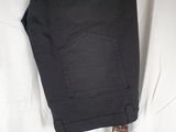 the back of a pair of black jeans laying on top of a white sheet