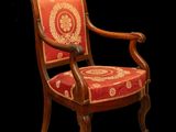 une chaise en bois dont l'assise est recouverte d'un tissu rouge et or