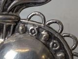 a silver vase that has a bird on top of it