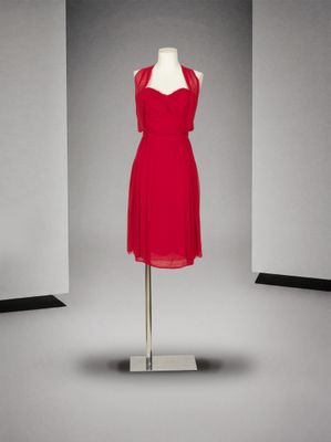 une robe rouge posée sur un pied de mannequin dans une pièce