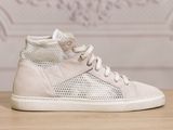 white high top sneakers on a wooden table with a wallpaper in the background