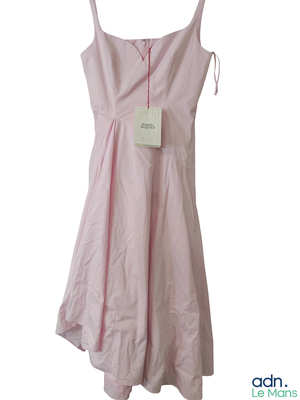 une robe rose suspendue à un cintre sur un mur blanc