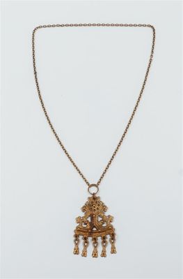a gold necklace with an ornate design on a chain