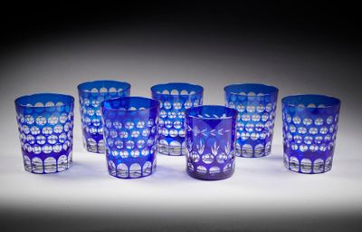 six verres en verre bleu sont alignés sur une surface blanche