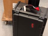 une valise noire posée par terre à côté d'une boîte