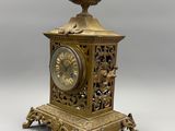 a gold clock with a bird on top of it