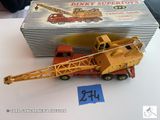 une grue miniature posée sur une boîte, elle-même posée sur une table