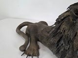 a statue of a lion that is laying down on a white surface