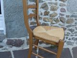 une chaise en bois posée devant un mur de pierre