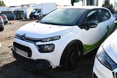 une voiture blanche avec une bande verte, garée sur un parking