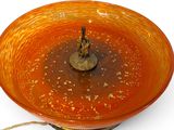 an orange bowl with a candle in it on a white surface