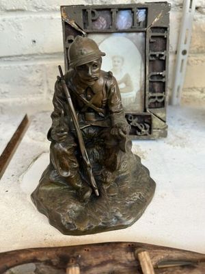 une statue en bronze représentant un soldat assis sur un rocher, un fusil à la main