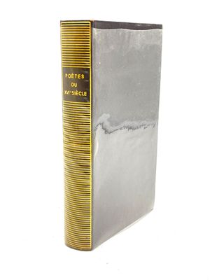 un livre argenté aux bords dorés posé sur une surface blanche