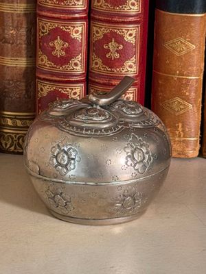 a silver apple shaped box sitting on a table next to a stack of books