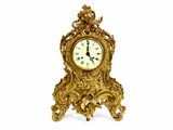 une horloge dorée posée sur un socle, sur fond blanc