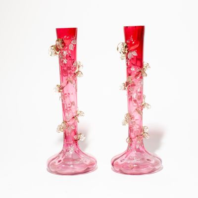 deux vases roses ornés de fleurs, posés sur une surface blanche
