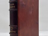 an old brown book with black bindings sitting on top of a white surface